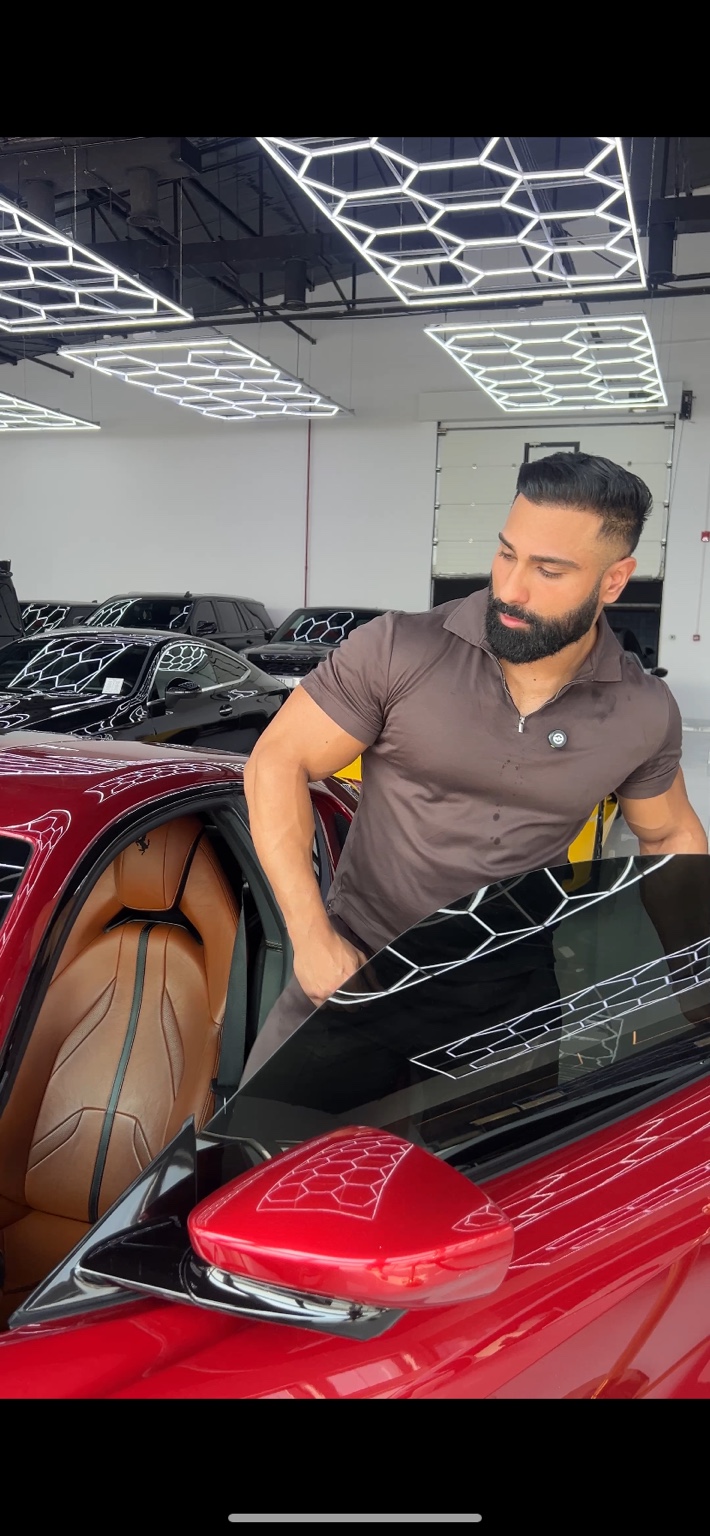 GURU beside a red Ferrari in a supercar showroom